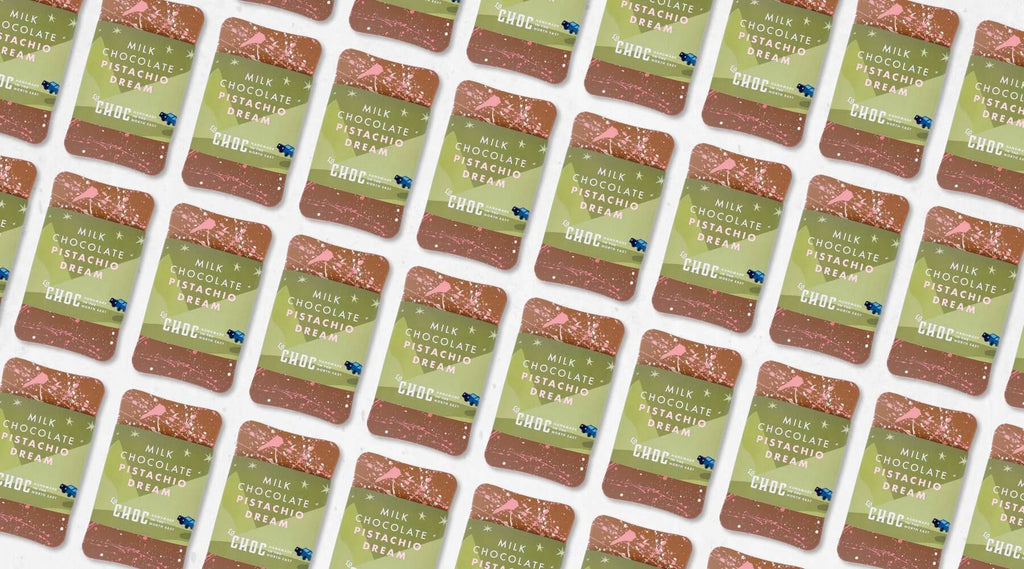 Assortment of handmade Milk Chocolate Pistachio Dream Bars by La Chocolatrice, showcasing green and pink artisan chocolate bar packaging.