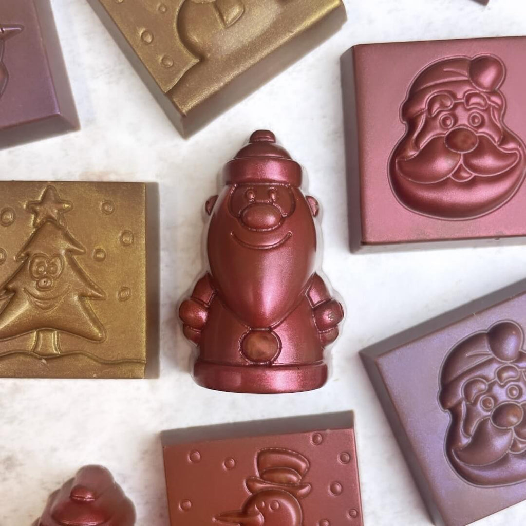 Assorted Christmas chocolates in various shapes, including Santa, a snowman, and a Christmas tree, displayed on a white background.