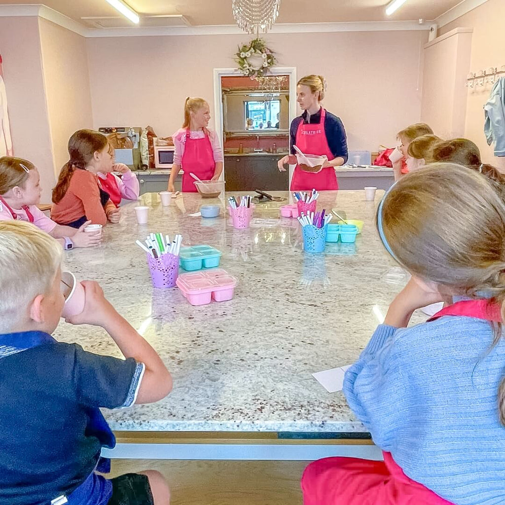 Kids attentively listening to an instructor at La Chocolatrice during a chocolate-making workshop.