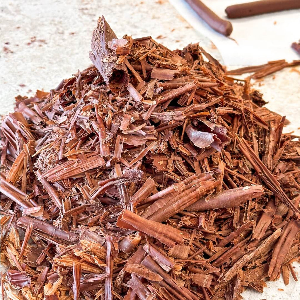 Close-up view of a pile of rich dark chocolate flakes used in La Chocolatrice workshops