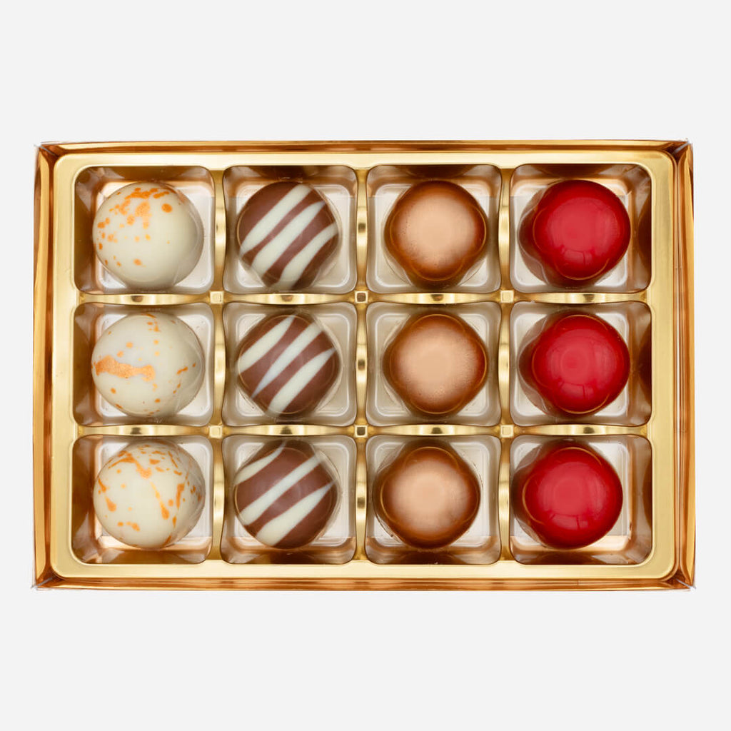Selection of handmade chocolate bonbons in gold tray from La Chocolatrice luxury collection.